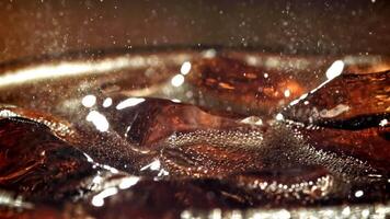 A glass of cola with ice. Splashes on the surface. Filmed on a high-speed camera at 1000 fps. High quality FullHD footage video