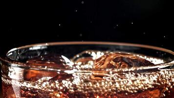 A glass of cola with ice. Splashes on the surface. Filmed on a high-speed camera at 1000 fps. High quality FullHD footage video