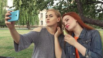 Two girls joyfully capturing a selfie in a sunlit park video