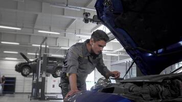 Dedicated car service technician meticulously checking oil in automobile with open hood video