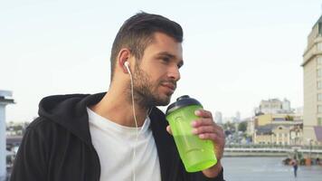 Athletic man enjoying hydration while listening to music video