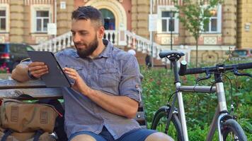 Caucasian cyclist engrossed in browsing the internet on his tablet video