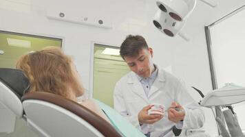 Young male dentist demonstrating proper tooth brushing techniques on a dental model video