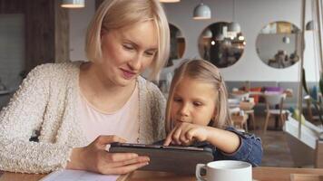 Mother and daughter share a joyful moment using a tablet at the cafe video