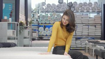Radiant woman beaming at the camera while seated on a plush bed in a stylish furniture store video