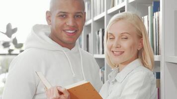 Joyful multiethnic couple beaming at the camera while sharing a book video