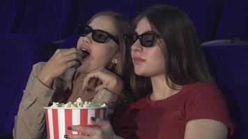 Two friends animatedly discuss a movie while enjoying popcorn in the cinema video
