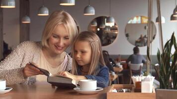 Mother and daughter share a joyful reading moment at the cafe video