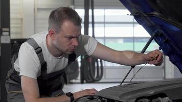 Dedicated auto mechanic meticulously checking oil levels in a car with an open hood video