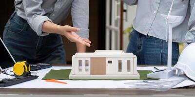 Eco-Friendly Building Models and Collaboration. Two architects discussing sustainable architecture with a focus on renewable energy. photo