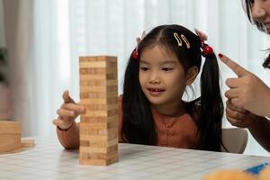 Back to School Activities and Games. A girl focuses on her stacking game with her mother, enhancing her concentration and skills. photo