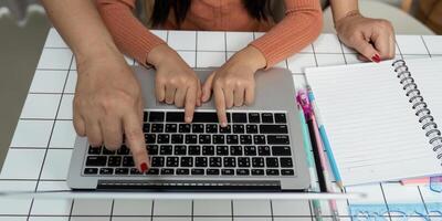 Back to School and Learning Together. A child and parent engaging in online learning, focusing on a laptop. photo