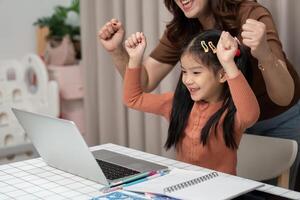 Back to School and Celebrating Success. A child rejoices after completing an online task with parental support. photo
