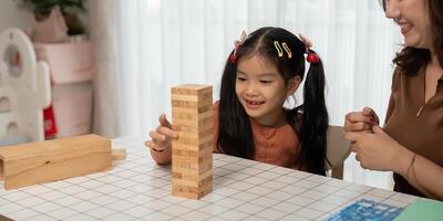 Back to School Fun and Learning. A young girl and her mother play a stacking game together, fostering creativity and bonding. photo