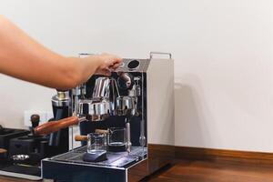 Barista hand presses a button while making fresh coffee. photo