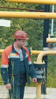 Engineer at the gas distribution complex makes a detour at the gas station. An employee of a gas production company works at a gas production station video