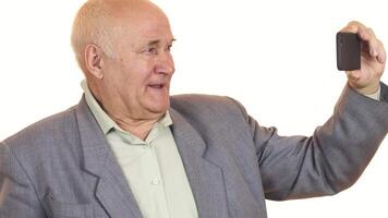 Joyful senior man smiling while taking selfies with a smartphone video