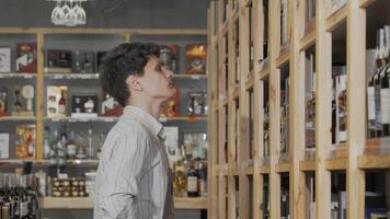 Young male winemaker meticulously arranging bottles on display in his vibrant store video