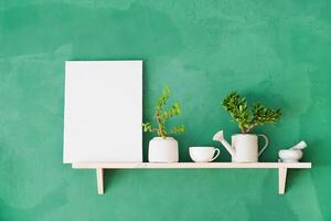 white canvas frame mockup for painting on shelf with decoration objects, rustic green wall photo