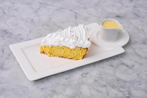 Tres Leches cake Slice with small bowl of extra milk sauce served in tray topped with fluffy whipped cream and saffron threads side view of indulgent dessert photo