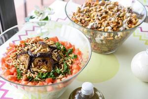 Assorted Salads in Glass Bowls include grains, vegetables, and nuts served on a table with dressing bottles closeup side view photo