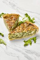 Delicious spinach and feta quiche slices with fresh arugula on marble photo