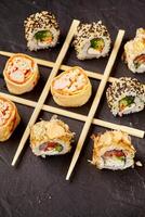Various sushi rolls forming tic-tac-toe game on dark background photo