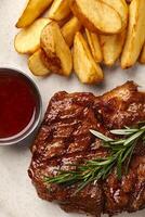 Grilled steak with potato wedges and red wine sauce, overhead view photo