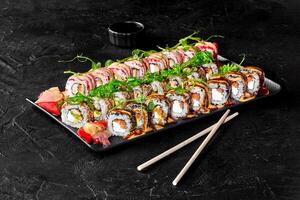 Sushi set with soy sauce, pickled ginger, wasabi, and sesame seeds on black stone background photo