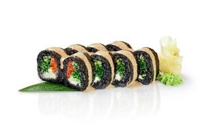 Black sushi rolls with salmon, vegetables and cream cheese drizzled with sauce on a green leaf photo