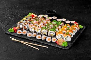 Sushi set with soy sauce, pickled ginger, wasabi and chopsticks on black stone plate photo