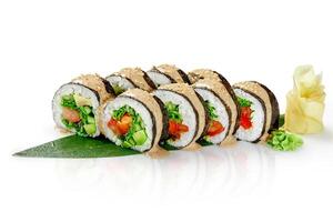 Vegan sushi rolls with vegetables and sesame seeds resting on a bamboo leaf photo