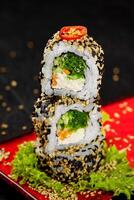 Stack of uramaki sushi rolls garnished with sesame seeds and chili pepper photo