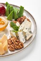 Plate presenting delicious cheese selection with honey and walnuts photo