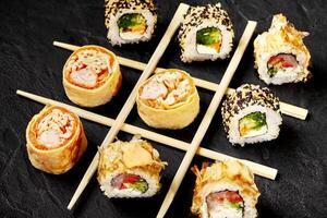 Sushi rolls forming a tic-tac-toe game on a black background photo