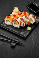 Sushi set presenting salmon philadelphia and eel uramaki rolls with soy sauce on black background photo