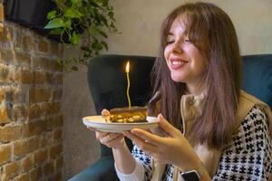 Brunette woman with cake and candle in cafe photo