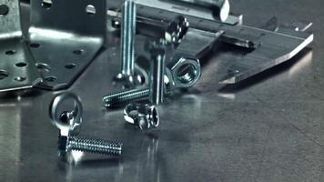 Falling nuts, bolts and washers on a metal table. Filmed on a high-speed camera at 1000 fps. High quality FullHD footage video