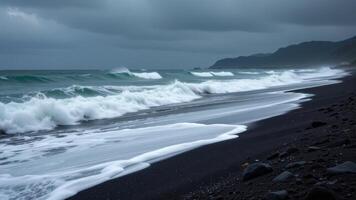 a stormy beach with black volcanic sand and crashing waves. photo