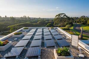 Aerial view of solar panels on a rooftop with plants and a scenic landscape in the background photo