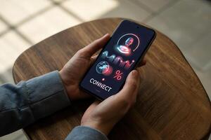 Person holding a smartphone displaying a connect interface on a wooden surface indoors view photo