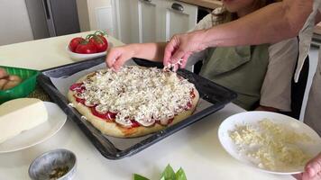 Grandmother and granddaughter adding mozzarella to pizza video
