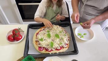 Grandmother and granddaughter adding basil leaves to pizza video
