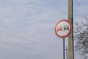 A no overtaking traffic sign is clearly visible beneath a cloudy sky, warning motorists effectively photo