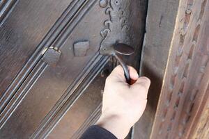 A hand gently reaching out for an intricately designed ornate door handle on a beautiful entrance photo