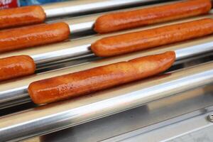 Sizzling Grilled Hot Dogs Being Cooked on a Roller Grill for Everyone to Enjoy Deliciously photo
