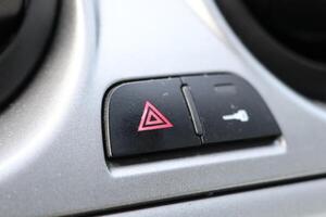 This specific button is designed to activate the emergency alert signal on a cars dashboard photo