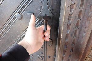 A hand grips an ornate door handle, highlighting its intricate artwork and elaborate design photo
