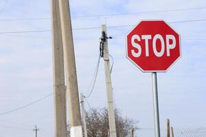 A Stop Sign positioned near a Utility Pole within a serene Rural Area surrounded by nature photo