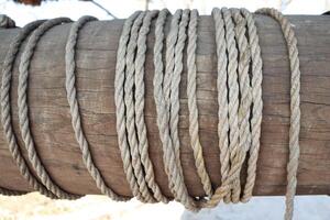 A Variety of Ropes Twisted and Tied Around a Wooden Post for Various Applications photo
